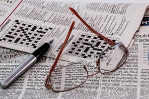 lunettes et journal avec grilles de mots croisés